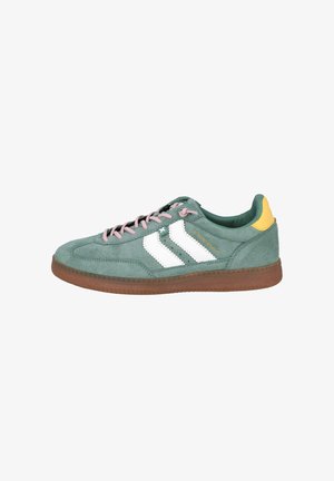 Zapatillas verdes de ante con rayas blancas y cordones rosas; presenta un acento amarillo en el talón y una suela de goma marrón.