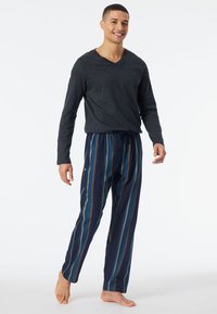 Men's V-neck long-sleeve shirt in dark gray, paired with navy pajama pants featuring vertical stripes in teal, olive, and brown.