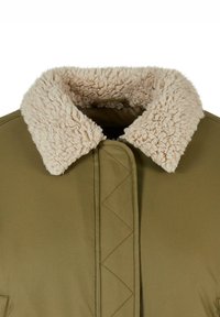 Giacca verde oliva con un colletto beige e peloso, dalla superficie esterna liscia e dettagli di cucitura a zigzag lungo la parte anteriore.