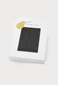 Czarna, prążkowana czapka beanie zaprezentowana w białym pudełku z przezroczystym oknem. Pudełko zawiera logo "TOMMY HILFIGER" oraz złotą metkę.