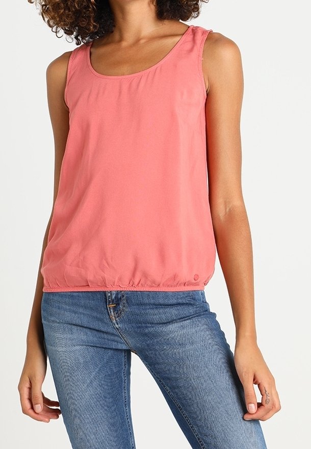 Top senza maniche color corallo con scollatura rotonda e orlo inferiore arricciato, realizzato in tessuto leggero. Abbinato a jeans di denim blu.
