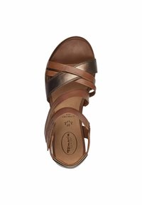 Sandale en cuir marron avec plusieurs brides croisées, une semelle intérieure rembourrée et une finition lisse ; présente un accent métallique et une bride de cheville réglable.