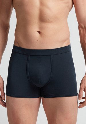 Dunkelblaue Boxer-Briefs aus einem weichen, dehnbaren Stoff zeichnen sich durch ein figurbetontes Design, kontrastierende Nähte und eine Vorderpocket zur Unterstützung aus.