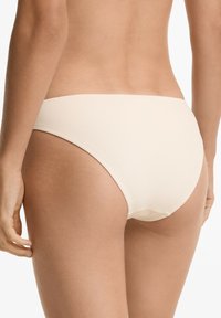 Svetlo bež bikini spodnji del z žametno teksturo, nizkim rezom in zmerno pokritostjo. Zaključene robove brez vidnih kovinskih delov ali dodatkov.