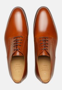 Scarpe eleganti in pelle marrone con finitura liscia, design con lacci, punta arrotondata e dettagli cuciti lungo la parte superiore. L'interno è beige.