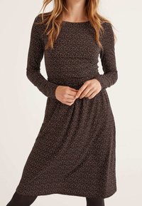 Robe à manches longues en tissu foncé avec de petits pois multicolores. Elle est dotée d'un corsage ajusté et d'une jupe fluide. Texture douce.