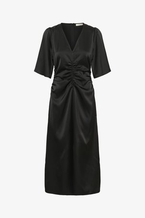 Juoda suknelė su V formos iškirpte, trumpomis pūstomis rankovėmis, surinktų detalių ties liemeniu ir sklandžios, lengvai krentančios medžiagos, siekiančios iki vidurio blauzdos.