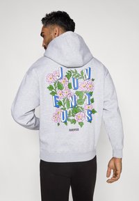 Hallhalline kapuutsidega, millel on suur lillemuster, kus on roosad lilled ja sinised tähed, mis kirjutavad "JUVENTUS" seljapäeval. Pehme kangas, mugav lõige.