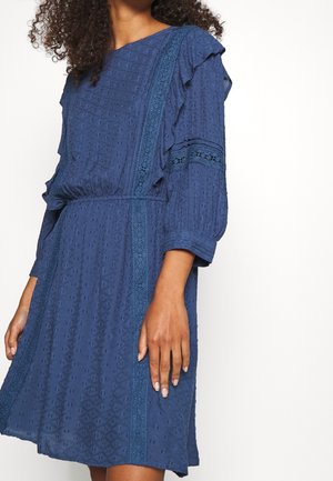 Marineblaues Kleid mit strukturierter Stoffqualität, Rüschenärmeln und Spitzenakzenten entlang der Nähte. Verfügt über eine taillierte Passform und einen entspannten Schnitt.