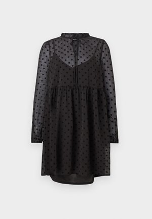 Mustas kleit, millel on poolläbipaistev täpidemuster, pikad varrukad, narmendav kaelus ja lahtine lõige, mis laieneb talje juures.