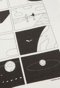 Camiseta gráfica con ilustraciones en blanco y negro de un paisaje, figuras y cuerpos celestes sobre un fondo de tela blanca.