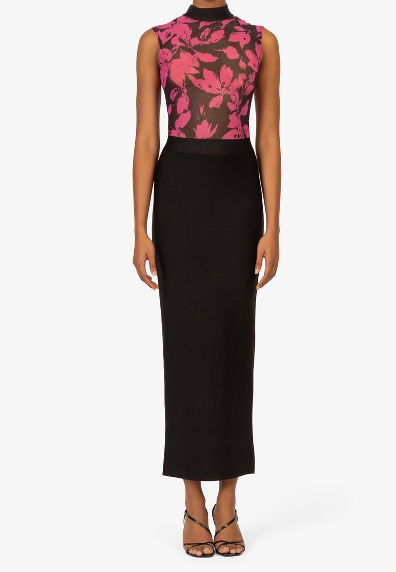 Jupe noire cintrée avec un corsage sans manches et transparent orné de fleurs dans un rose vif. Le col montant ajoute de l'élégance à l'ensemble.