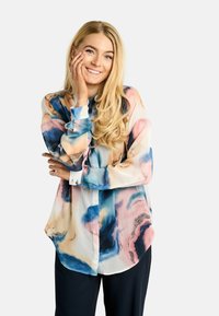 Hosszú ujjú ing áttetsző anyagból, rózsaszín, kék és krémszínű absztrakt vízfesték mintával. Gombos mandzsetták és ívelt alsó szegély.
