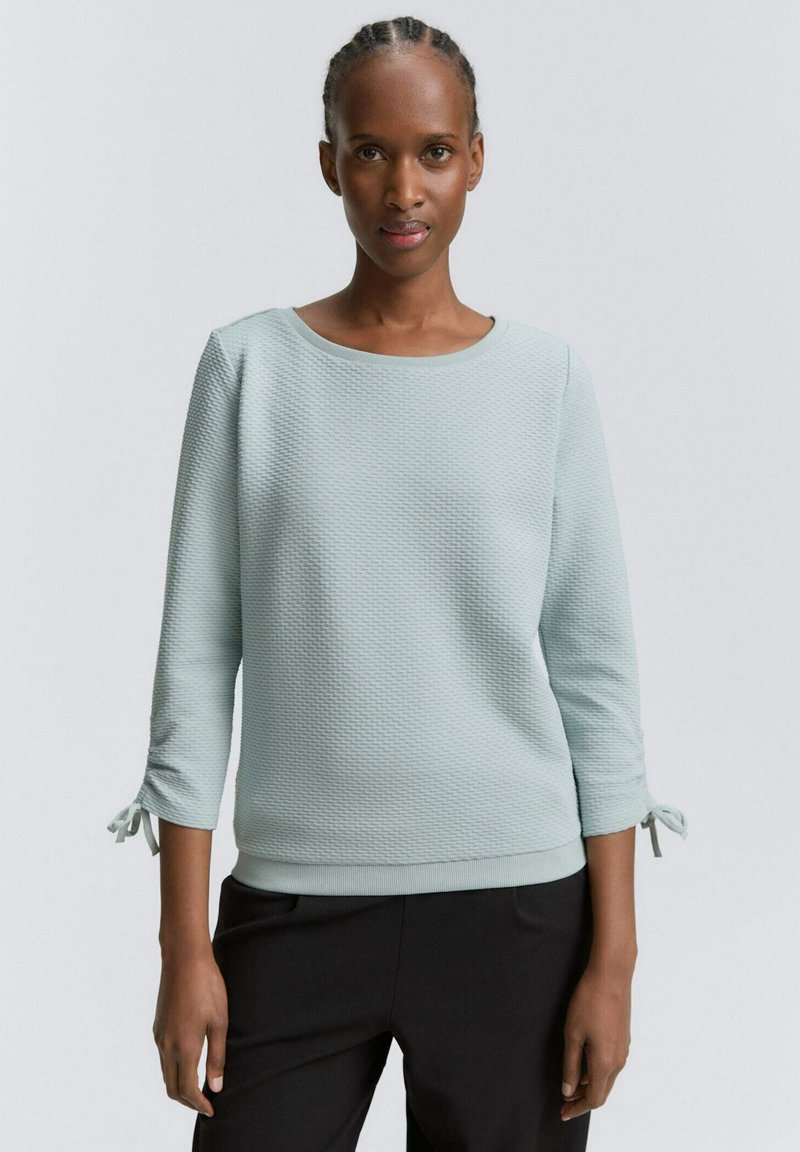 Svetlomodrá textúrovaná mikina s okrúhlym výstrihom, trojštvrťovými rukávmi s viazaním na manžetách a rebrovaným lemom.