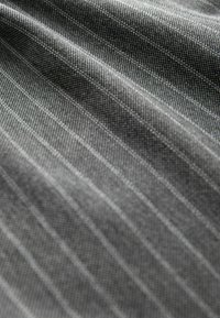 Szürke textil finom bordázott mintázattal, amelyen diszkrét függőleges csíkok találhatók. Az anyag sima felszínű, sűrű szövésű.