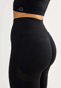 Leggings neri a vita alta in tessuto testurizzato, caratterizzati da un design senza cuciture e un logo a forma di cuore sulla vita per un miglior comfort e vestibilità.
