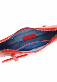 Borsa di pelle rossa con zip argentata, con interni in tessuto blu e una tasca interna. Include un tirazip a forma di croce di un rosso brillante.