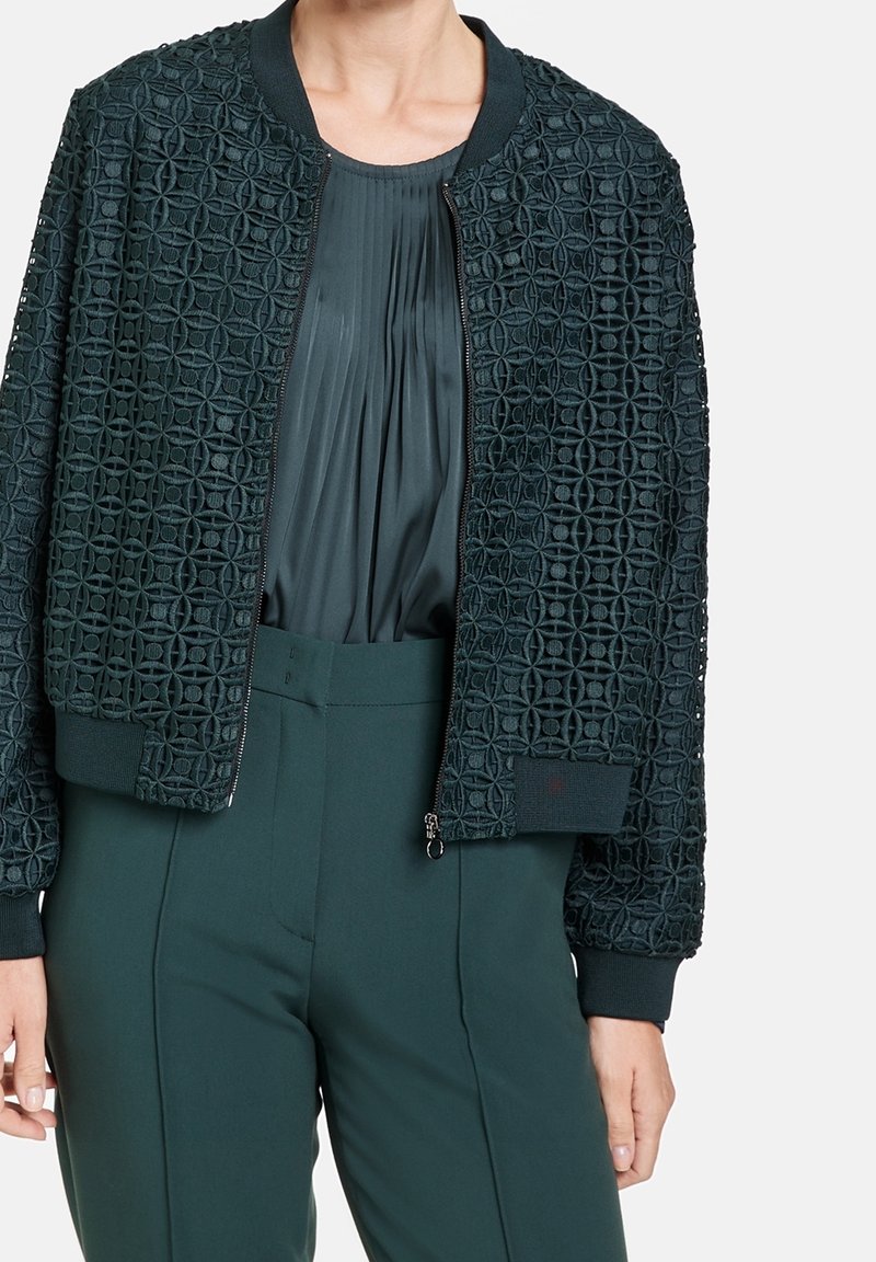 Tummaa vihreä pommik jacket, jossa on teksturoitu geometrinen kuvio, resorikankaiset hihansuut ja kaulus sekä edessä vetoketju. Yhdistetty laskostettuun puseroon.