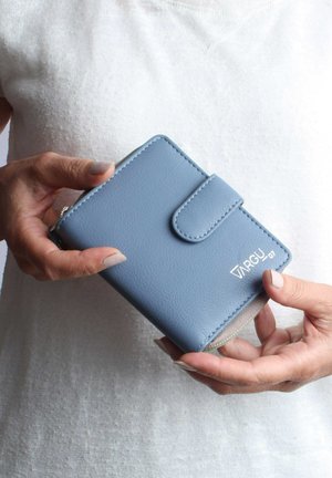 Blue leather wallet with a textured finish, featuring a flap closure and silver logo detail, held in hands against a light background.