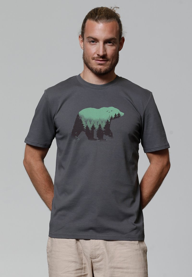 T-shirt en coton gris avec un graphisme représentant un ours entouré d'arbres verts. Manches courtes et col rond. Texture lisse, coupe décontractée.