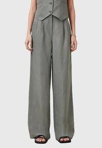 Lichtgrijze wijde broek van een gestructureerde stof met plooien, gecombineerd met een nauwsluitende vest. Kenmerkt zich door een hoge taille en een ontspannen silhouet.