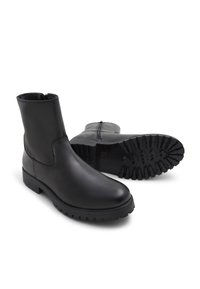 Botas negras de cuero hasta el tobillo con un acabado suave, suela texturizada en contraste y cierre de cremallera en la parte posterior. Suela con dibujo resistente para un mejor agarre.