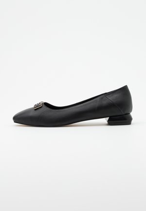 Bailarinas negras de cuero con punta afilada, pequeño tacón bloque y un acento metálico decorativo en el empeine. Textura suave y diseño elegante.