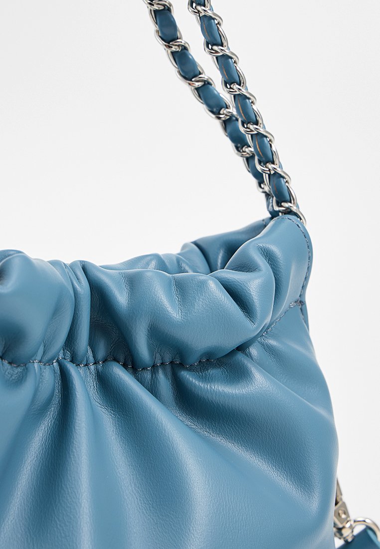 Sac à main en cuir bleu avec un haut froncé et une bandoulière en chaîne argentée tissée de cuir bleu assorti.