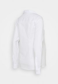 Camisa branca de manga longa com colarinho clássico, mangas abotoadas e uma textura suave de algodão. Apresenta um design de costas retas.