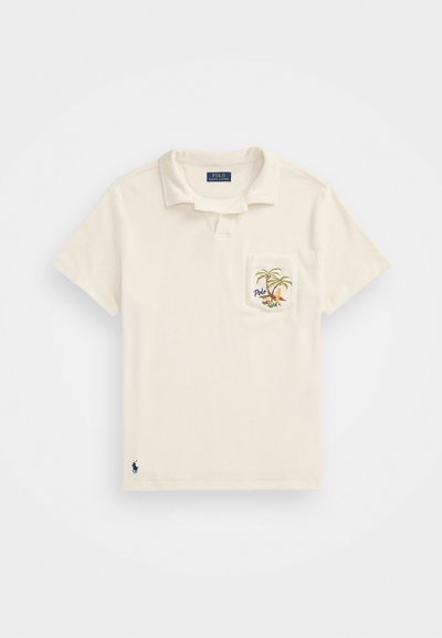 Krämfärgad polo skjorta med korta ärmar, krage och en bröstficka med broderi av palmträd. Marinblått logotyp vid nederkanten och etikett. Bomullsmaterial.