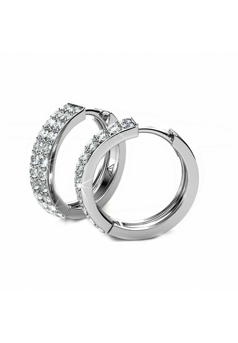 Orecchini a cerchio in argento con una fila di strass trasparenti e scintillanti lungo il bordo esterno. Superficie metallica liscia con una finitura lucida.