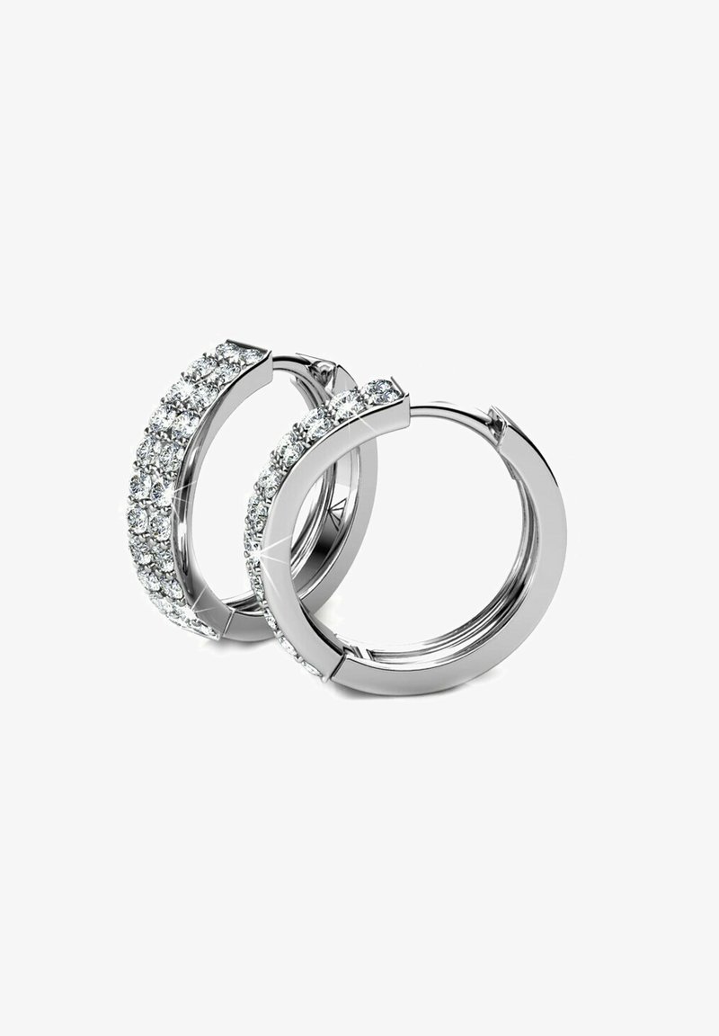 Orecchini a cerchio in argento con una fila di strass trasparenti e scintillanti lungo il bordo esterno. Superficie metallica liscia con una finitura lucida.