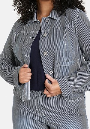 Vrouw die een opengeknipte blauw-wit gestreepte jas en bijpassende broek aanpast, over een donker topje.