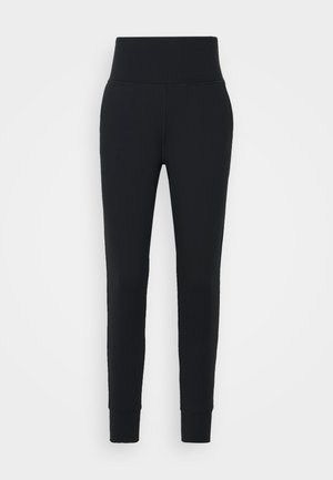 Pantalon noir taille haute, coupe slim, avec bas de jambes resserrés aux chevilles, présenté sur un fond blanc uni.