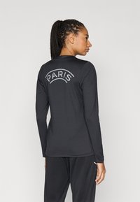 Fekete hosszú ujjú sportfelső, hátul ívelt "PARIS" felirattal szürke színben. Simább textúrájú és testhez simuló kialakítású.