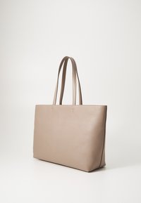 Sac fourre-tout en cuir beige avec deux longues poignées, de forme rectangulaire, texture lisse et design minimaliste, présentant des accents gaufrés subtils.