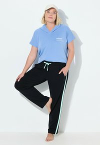 Jasnoniebieska bluza z kapturem i krótkimi rękawami, zestawiona z czarnymi spodniami z miętowozielonymi paskami po bokach i ściągaczem w pasie.