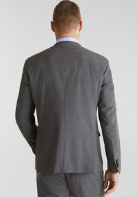 Blazer grigio con tessuto texturizzato, spacco singolo sul retro e polsini con due bottoni. Design strutturato con una silhouette dritta.