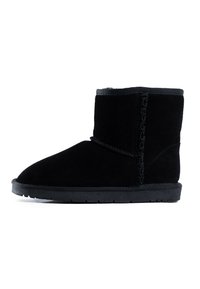 Botines de ante negros con suela plana de goma, que presentan costuras laterales y un detalle texturizado a lo largo de la costura. Diseño simple y redondeado.