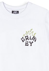 Camiseta de algodón blanca con un diseño gráfico en negro que dice "GRIMEY" acentuado con llamas verdes arriba. Cuello redondo y mangas cortas.