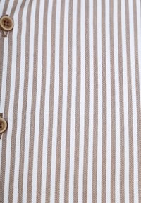 Knopen-overhemd met dunne bruine en witte verticale strepen. Katoenen stof met een gladde textuur en een enkele bruine knoopdetail.