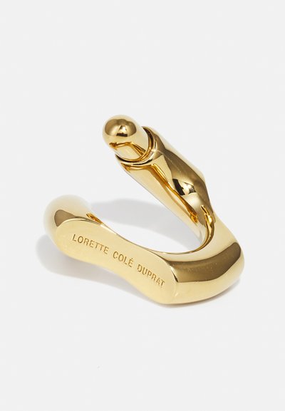 Gouden, gebogen metalen haak met een gladde textuur en een ronde punt. Gegraveerd "LORETTE COLÉ DUPRAT" op de platte zijde.