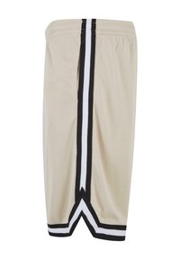 Shorts de sport beige en tissu mesh, avec des rayures verticales noires et blanches et une fente au niveau de l'ourlet.