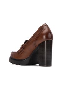 Scarpa con tacco alto in pelle marrone, con punta arrotondata, piattaforma nera texturizzata e tacco quadrato rigato. Superficie liscia con dettagli di cucitura minimi.