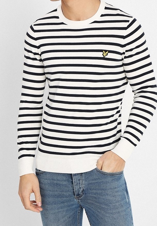 Suéter a rayas en blanco y negro, con cuello redondo, puños y dobladillo acanalados. Pequeño logo amarillo en el pecho. La tela parece suave y ligera.