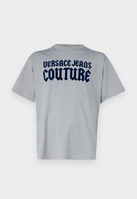 T-shirt a maniche corte grigio chiaro con il testo audace navy "Versace Jeans Couture" che attraversa la parte superiore della schiena.