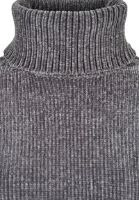 Gros plan d'un tissu de pull à col roulé en maille épaisse, gris côtelé, montrant des lignes verticales douces et texturées.