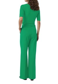 Haut vert à manches courtes côtelé associé à un pantalon large taille haute vert, avec une texture lisse et une coupe soignée.
