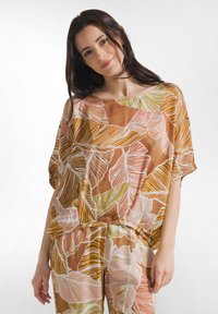 Løs bluse lavet af letvægtsstof med en brun baggrund og store, farverige bladmønstre i nuancer af orange, grøn og pink.