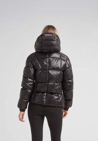Giubbotto puffa nero con cappuccio, dal finish lucido, con motivo trapuntato, polsini elastici e lunghezza media.
